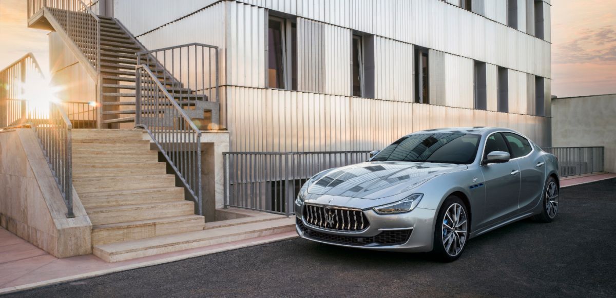 Silver Maserati outside a white building